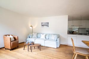 a living room with a white couch and a table at Chasa Serras Kuemin in Scuol +10 photos