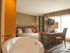 un bagno con vasca e una camera con letto di Olimpia Hotel a Bormio