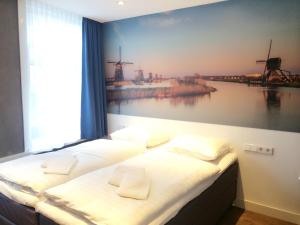 a bedroom with three beds and a painting of windmills at The Old Nickel Hotel in Amsterdam
