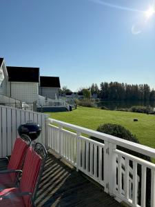 a deck with two chairs and a grill on it at Kinsale Lodge · Cotswolds Lakeside - Spring Lake in South Cerney