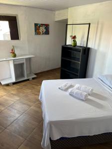 a bedroom with a white bed with towels on it at Destino Hospeda in Pipa