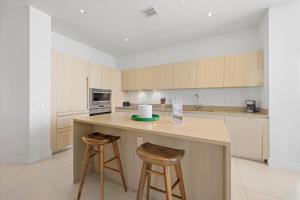 a kitchen with wooden cabinets and a counter with two stools at Beautiful Beachfront Penthouse in Hollywood +48 photos