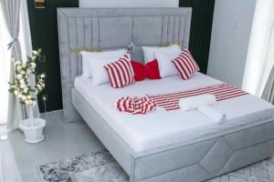 a white bed with red and white pillows on it at Fully furnished apartment in Nyali near the beach in Mombasa +8 photos
