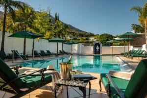 a swimming pool with chairs and umbrellas in a resort at Grande Roche Hotel in Paarl