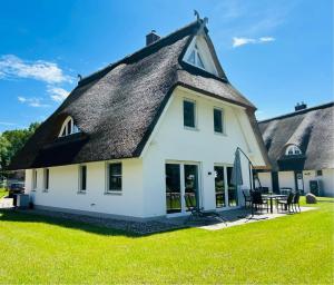a thatched roof house with a green lawn at Reetdach-Ferienhaus "ANNI" mit direktem Meerblick, Sauna und Kamin in Pepelow