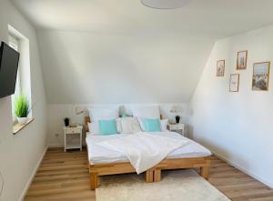 a white bedroom with a bed with blue pillows at Reetdach-Ferienhaus "ANNI" mit direktem Meerblick, Sauna und Kamin in Pepelow