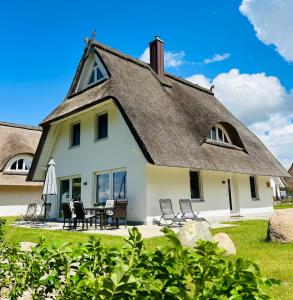 a thatched roof house with chairs and a table at Reetdach-Ferienhaus "ANNI" mit direktem Meerblick, Sauna und Kamin in Pepelow