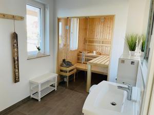 a bathroom with a sink and a desk in a room at Reetdach-Ferienhaus "ANNI" mit direktem Meerblick, Sauna und Kamin in Pepelow +19 photos