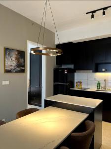 a kitchen with black cabinets and a table with chairs at KL Suites Axon Residence - Wi-Fi 500Mbph in Kuala Lumpur