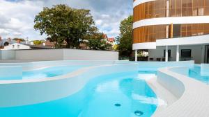 a swimming pool with blue water in front of a building at VacationClub - Baltic Waves Resort Apartament A118 in Międzyzdroje