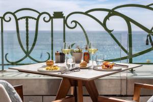 a table with two plates of food and glasses of wine at Hyatt Regency Nice Palais de la Méditerranée in Nice