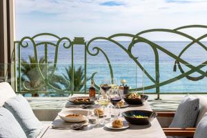 a table with food and wine glasses and a view of the ocean at Hyatt Regency Nice Palais de la Méditerranée in Nice
