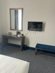 a room with a bed and a desk and a television at Hotel Baba in Uddingston