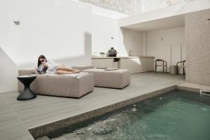 a woman sitting on a couch next to a swimming pool at Casa da Fé in Lagoa