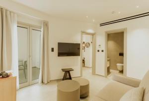 a white living room with a couch and a tv at Opal Paros in Naousa