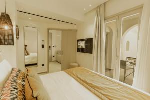 a white bedroom with a bed and a mirror at Opal Paros in Naousa