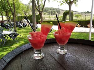 three cocktails sitting on a wooden table with watermelon at Chalet con piscina in Pinoso