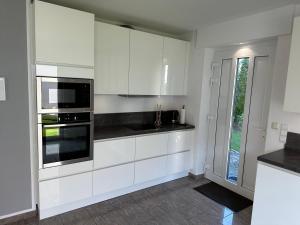 Eine weiße Küche mit weißen Schränken und einer Mikrowelle in der Unterkunft Ferienwohnung Forstblick in Kranenburg