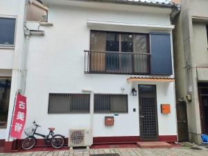 a white house with a bike parked in front of it at Hotel Relation in 門司港 in Kitakyushu