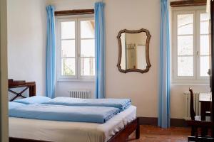 a bedroom with a bed with blue curtains and a mirror at Albergo Casa Santo Stefano in Miglieglia +33 photos