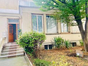 a house with a blue door and a tree at Maisonnette au calme proche T2 in La Garenne-Colombes