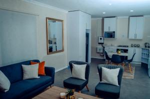 a living room with a couch and chairs and a kitchen at Estate Apartments in Lusaka