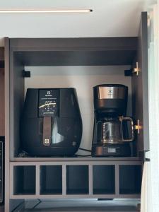 une cafetière et une cafetière sur une étagère dans l'établissement Apto Studio 514 no RN Studio Premium em Maceió, à Maceió