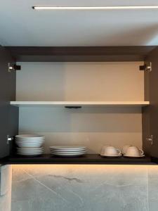 une cuisine avec des bols et des assiettes sur une étagère dans l'établissement Apto Studio 514 no RN Studio Premium em Maceió, à Maceió 65 autres photos