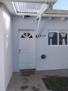 un edificio blanco con una puerta blanca y una ventana en La casita, en El Calafate