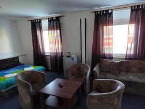 a hotel room with a bed and a couch and chairs at Penzion Agrothermal in Bešeňová