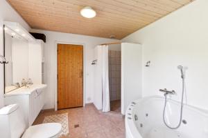 a bathroom with a tub and a toilet and a sink at Beautiful Holiday Home In Mols Close To The Water in Knebel +13 photos