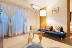 een woonkamer met een blauwe bank en een glazen tafel bij Cozy Stay Sapporo Central Nakajima in Toyohira