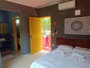 a bedroom with a bed and a yellow door at Pousada ZEN Cumuruxatiba in Cumuruxatiba +37 photos