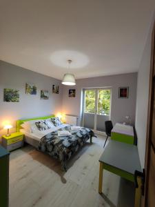 a bedroom with a bed and a desk and a window at Apartament Astra - Bliżej Zdroju in Polanica-Zdrój