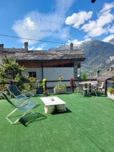 eine Terrasse mit Stühlen und einem Tisch sowie ein Tisch und Stühle in der Unterkunft Le Glacier in La Salle