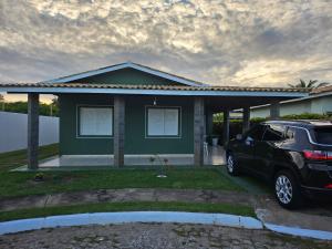 a car parked in front of a green house at Casa de Paraia em Aracaju in Aracaju