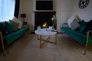 a living room with two green couches and a coffee table at Dundrine Cottage in Maghera