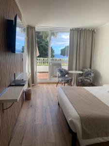 a hotel room with a bed and a large window at Les Alcyons in Le Lavandou