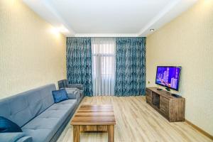a living room with a blue couch and a tv at Magnificent Vacation apartment by Bea Paradise in Baku