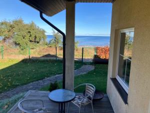 a patio with a table and chairs and a view of the ocean at Pirts cottage in Kaltene