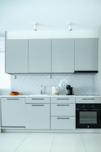 a white kitchen with white cabinets and a black oven at New apartment with 80m2 garden close to Torrevieja Alicante in San Miguel de Salinas +40 photos