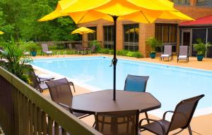 a table with an umbrella next to a swimming pool at Wyndham Garden Williamsburg Busch Gardens Area in Williamsburg
