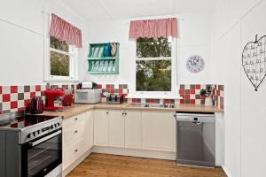a kitchen with white cabinets and red and white tiles at Historic Corinda Cottage in Bundanoon