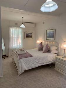 ein Schlafzimmer mit einem großen Bett mit Kissen darauf in der Unterkunft Historic Corinda Cottage in Bundanoon