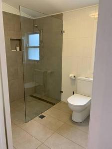 ein Badezimmer mit Toilette und Glasdusche in der Unterkunft Historic Corinda Cottage in Bundanoon + 8 Fotos