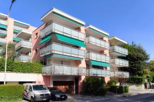 a pink building with cars parked in front of it at Francobollo Studio by Quokka 360 - flat with balcony in Massagno +18 photos