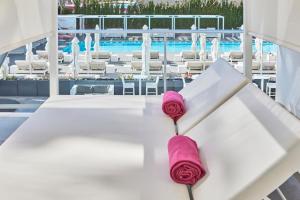 a pair of pink roses sitting on a table next to a pool at Hotel Astoria Playa Adults Only 4* Sup in Port d'Alcudia