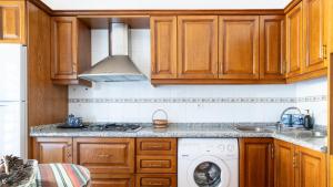 a kitchen with wooden cabinets and a washing machine at Huerta La Niña Arenas Órgiva by Ruralidays in Órgiva