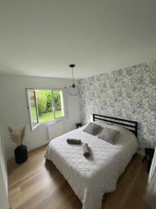 Néant-sur-YvelMaison cosy的卧室配有一张带白色棉被的床和窗户。