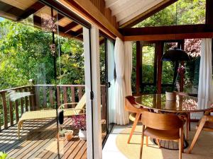 a screened in porch with a table and chairs at Pousada Caminho do Rei in Praia do Rosa
